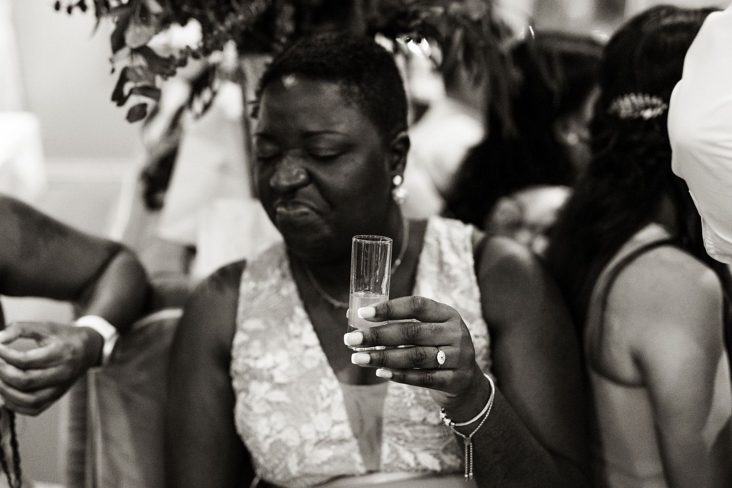 Black and white photo of a wedding guest raising a champagne flute during a heartfelt toast.