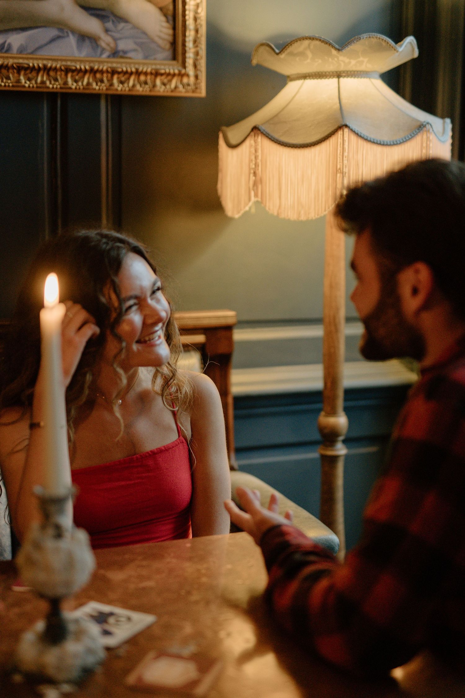 Woman smiling warmly at a man by candlelight in an elegantly decorated vintage interior.