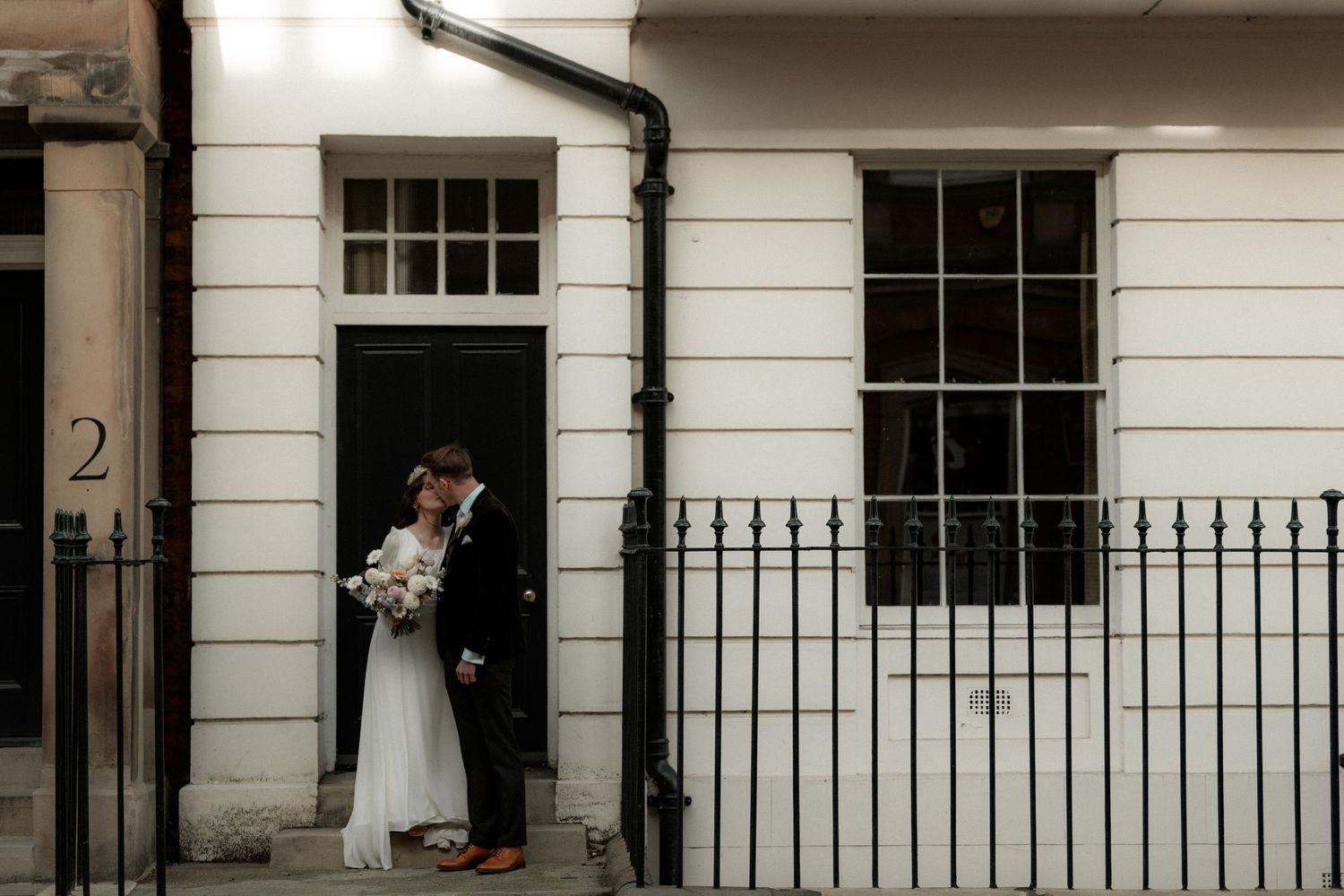 Intimate wedding portrait of couple by classic Georgian townhouse with iron railings.