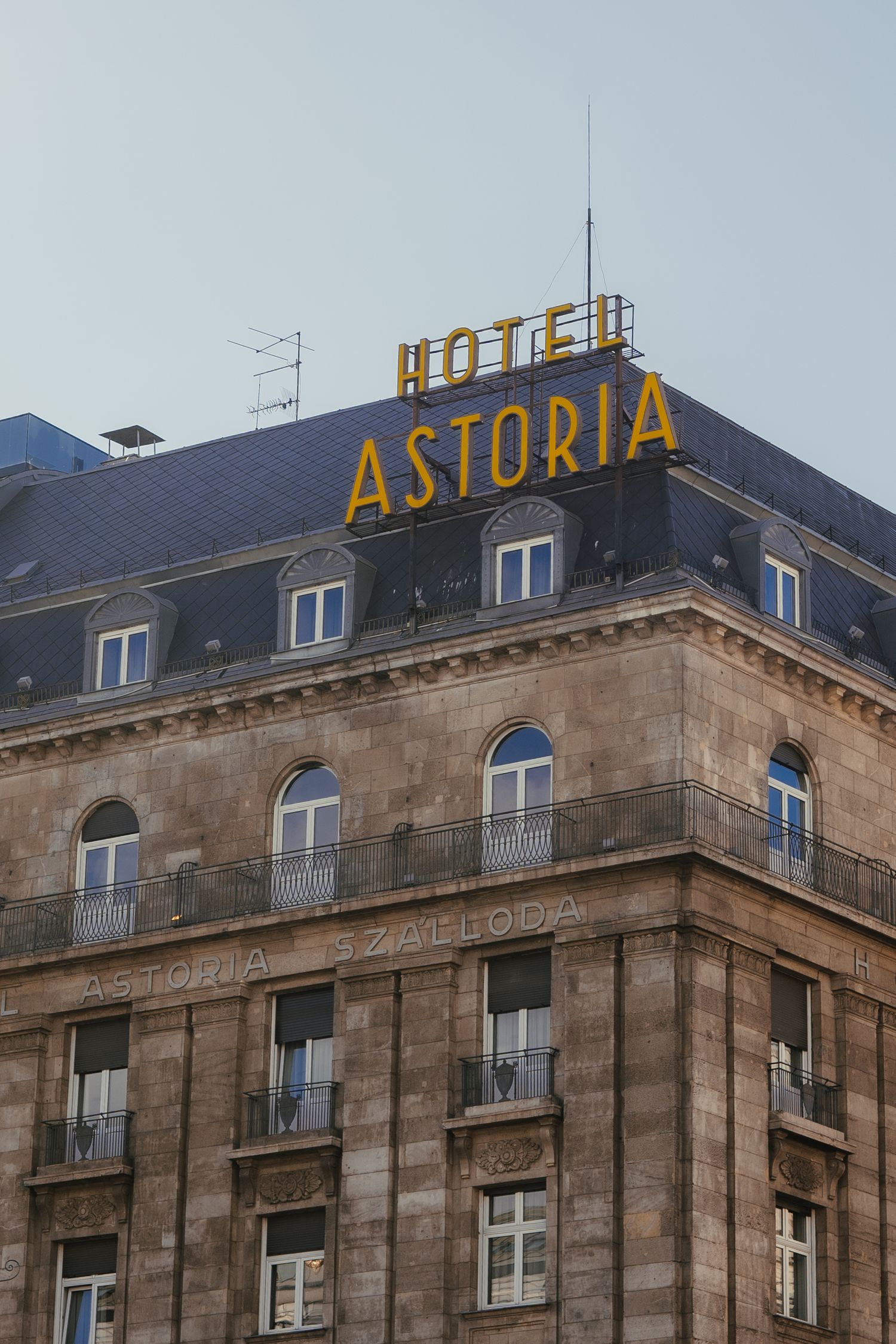 Historic Hotel Astoria building exterior with yellow rooftop signage and classic architectural details in urban setting.