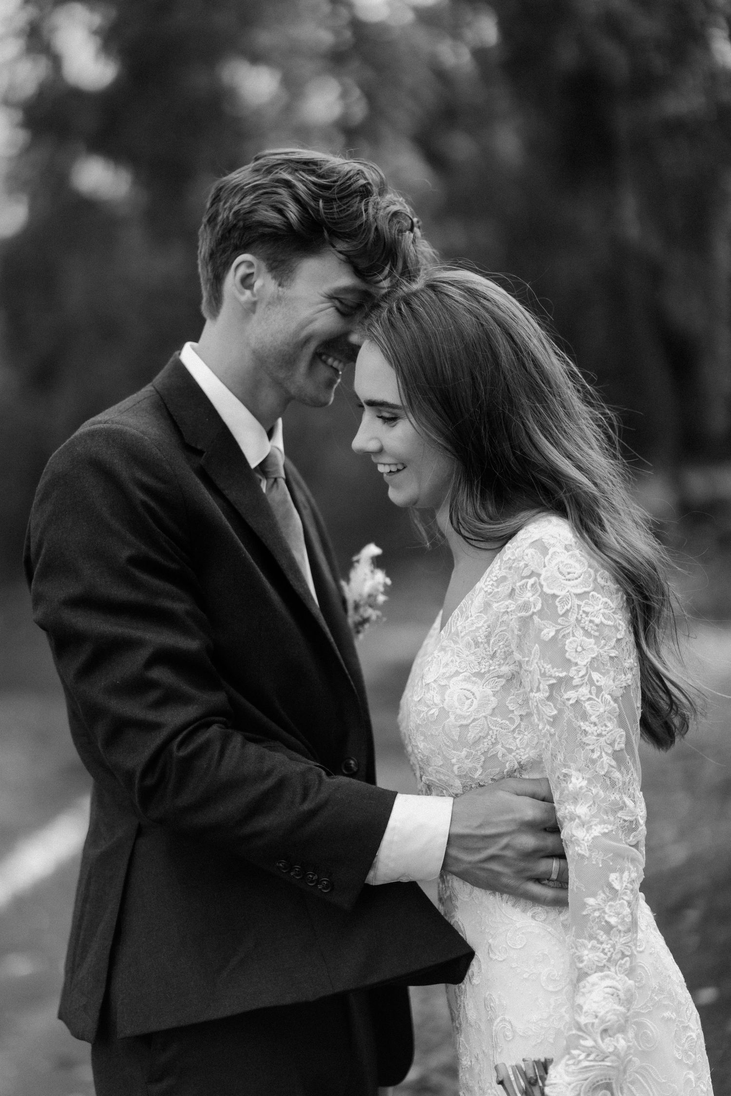 Black and white portrait of smiling bride and groom embracing closely on their wedding day.