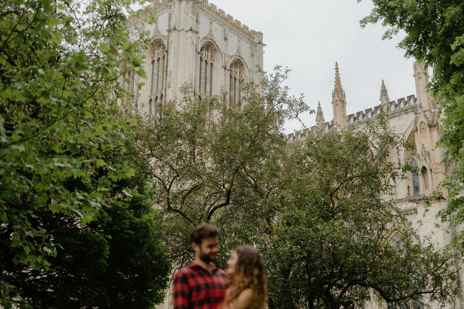 Couple embracing in front of the stunning Gothic architecture of York Minster cathedral.