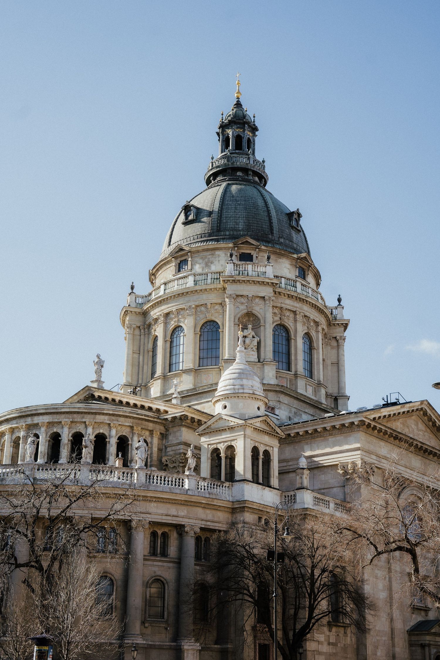The ornate dome and classical architecture of the Budapest Basilica rises against a clear blue sky in Hungary.