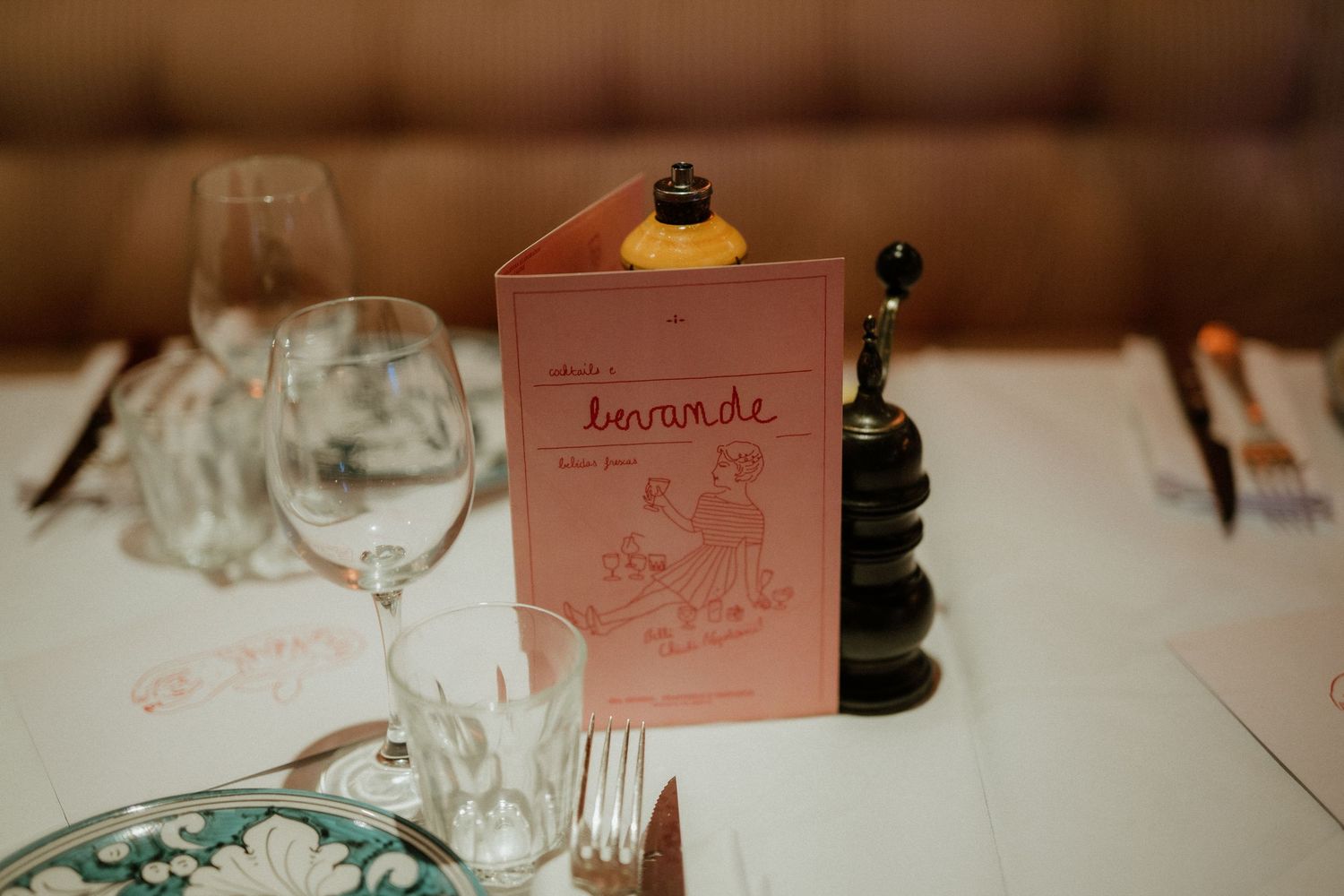 Elegant wedding place setting with pink menu card, wine glasses, and pepper mill.