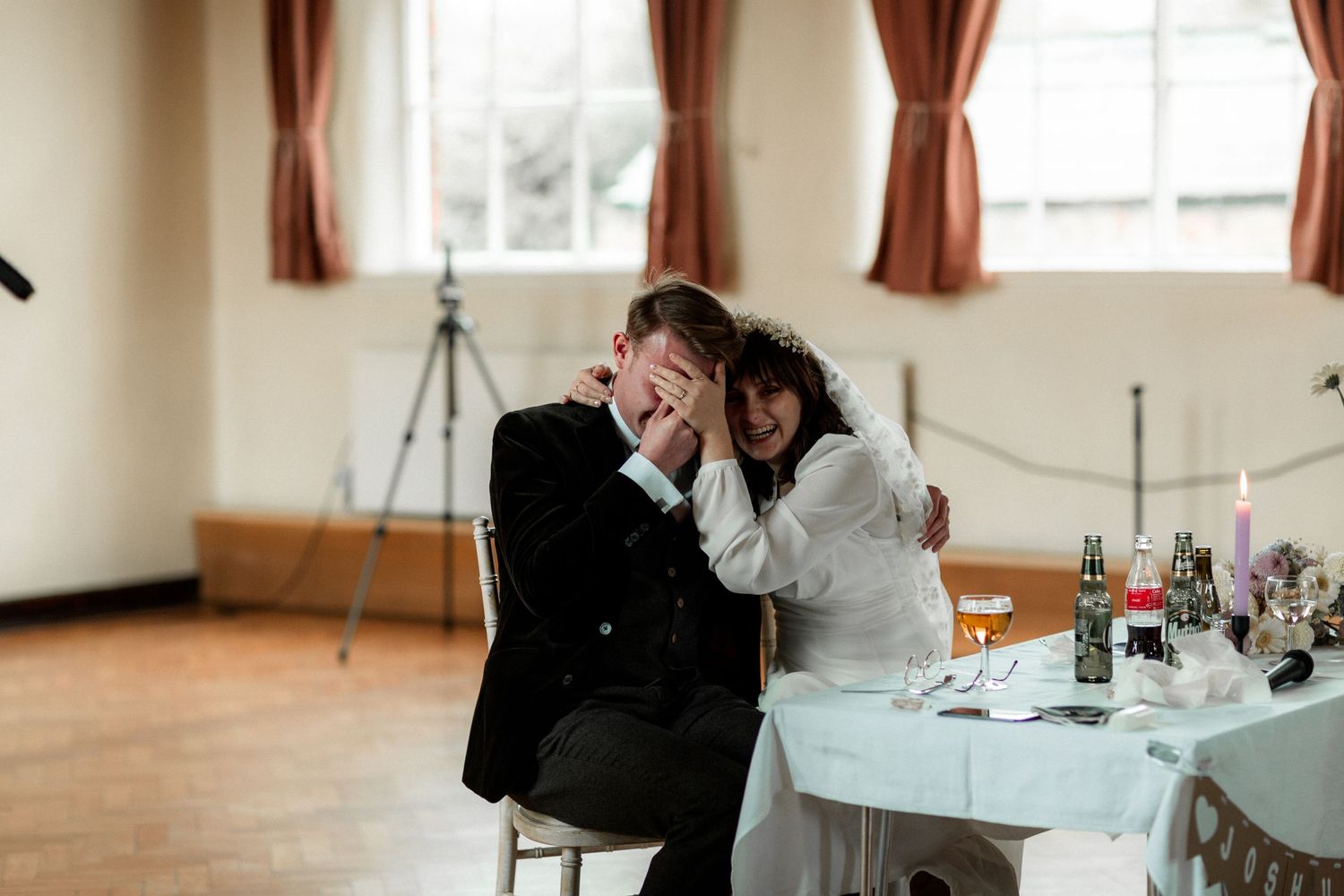 A candid moment of shared laughter at a wedding reception with rustic decor.