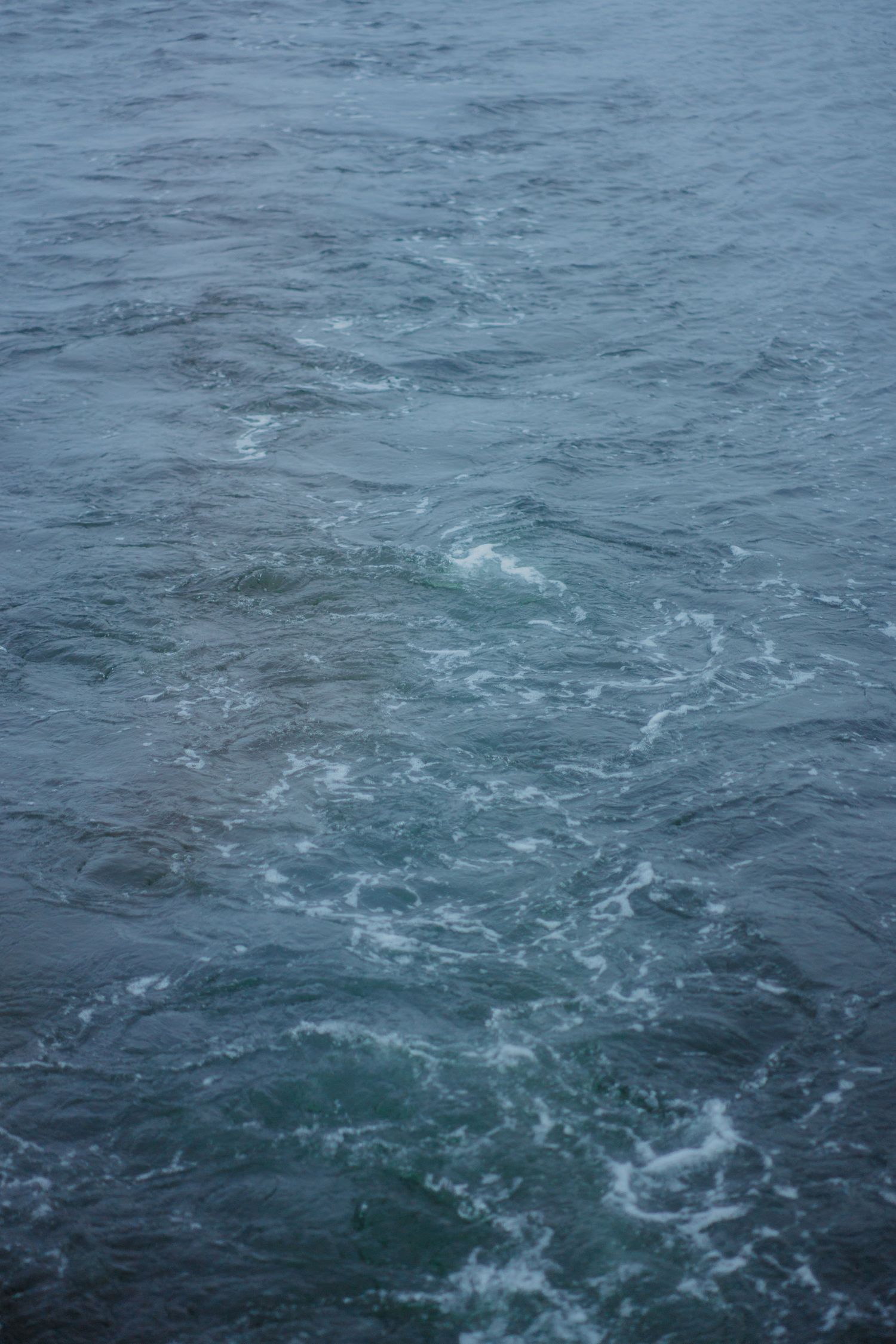 Dark blue ocean water with white foam and ripples creating a turbulent surface pattern in the fjord of Oslo