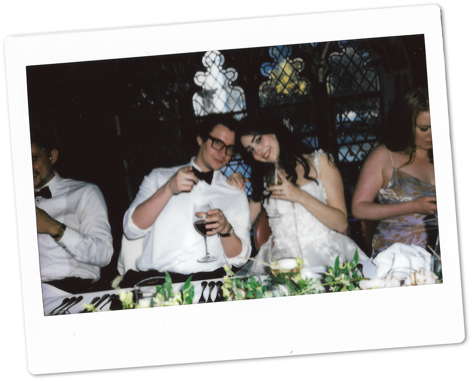 Bride and groom toasting with wine glasses at head table in Polaroid photo.