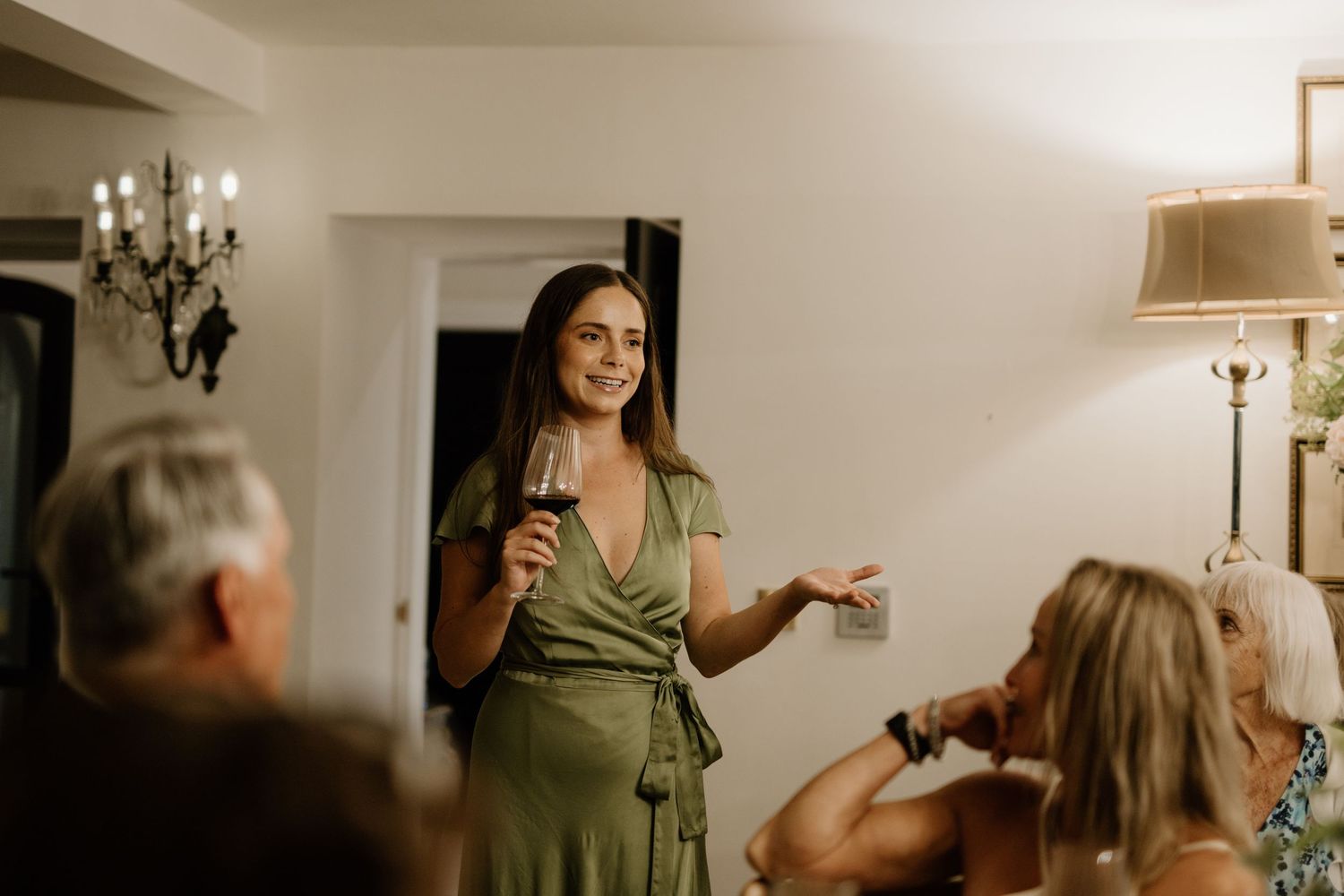 Woman in green dress giving a toast speech at an intimate wedding reception.