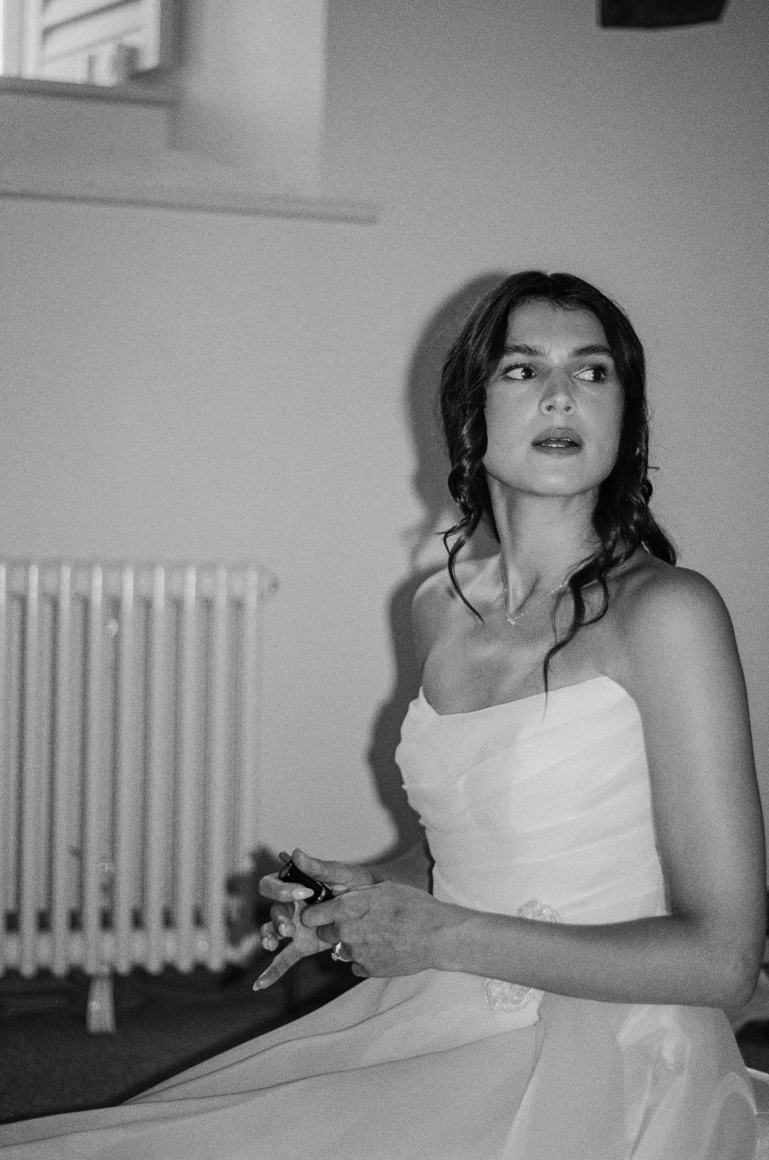 Black and white portrait of bride in strapless gown sitting thoughtfully before wedding.