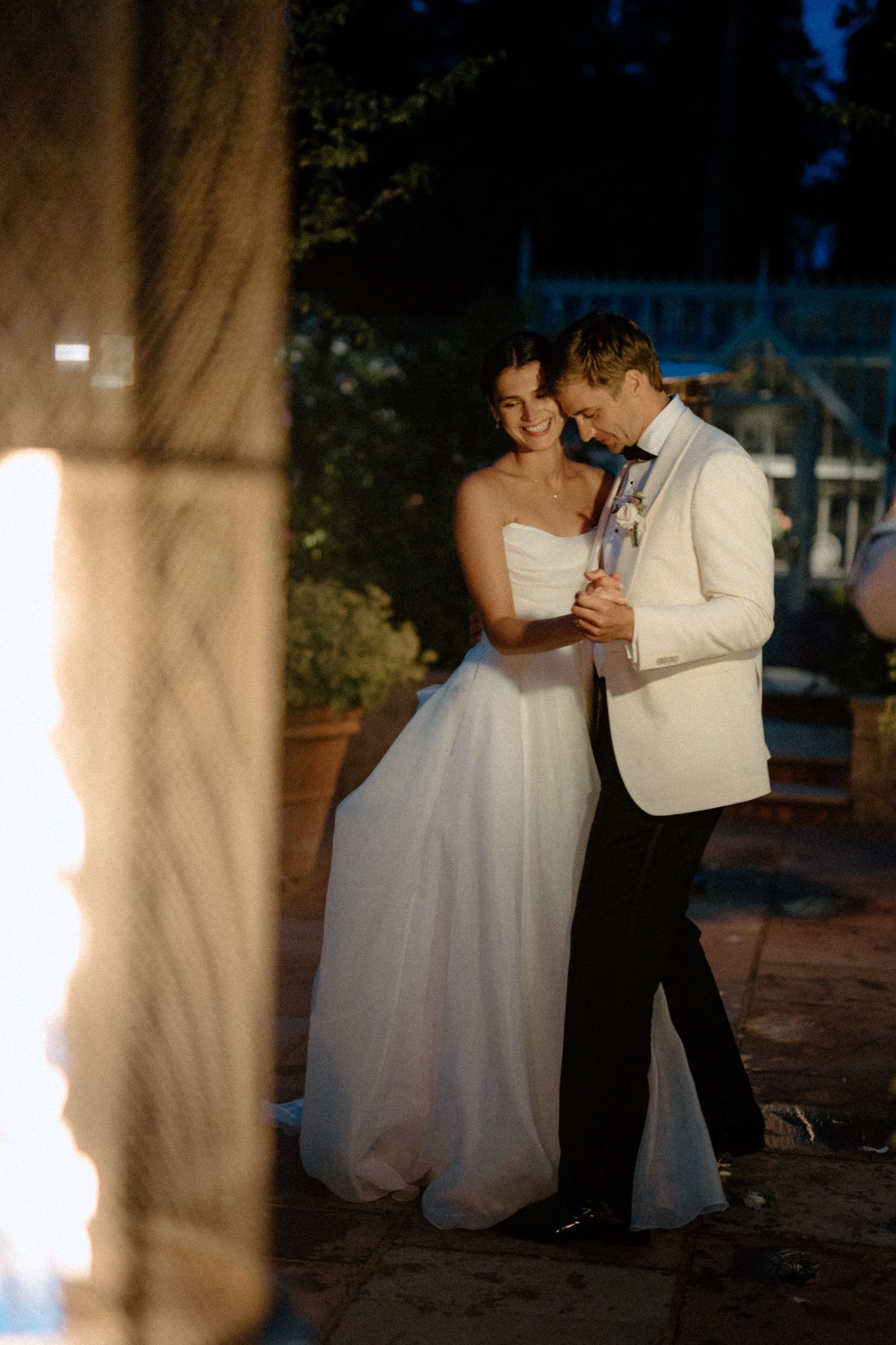 Bride and groom sharing first dance outdoors at golden hour wedding reception.