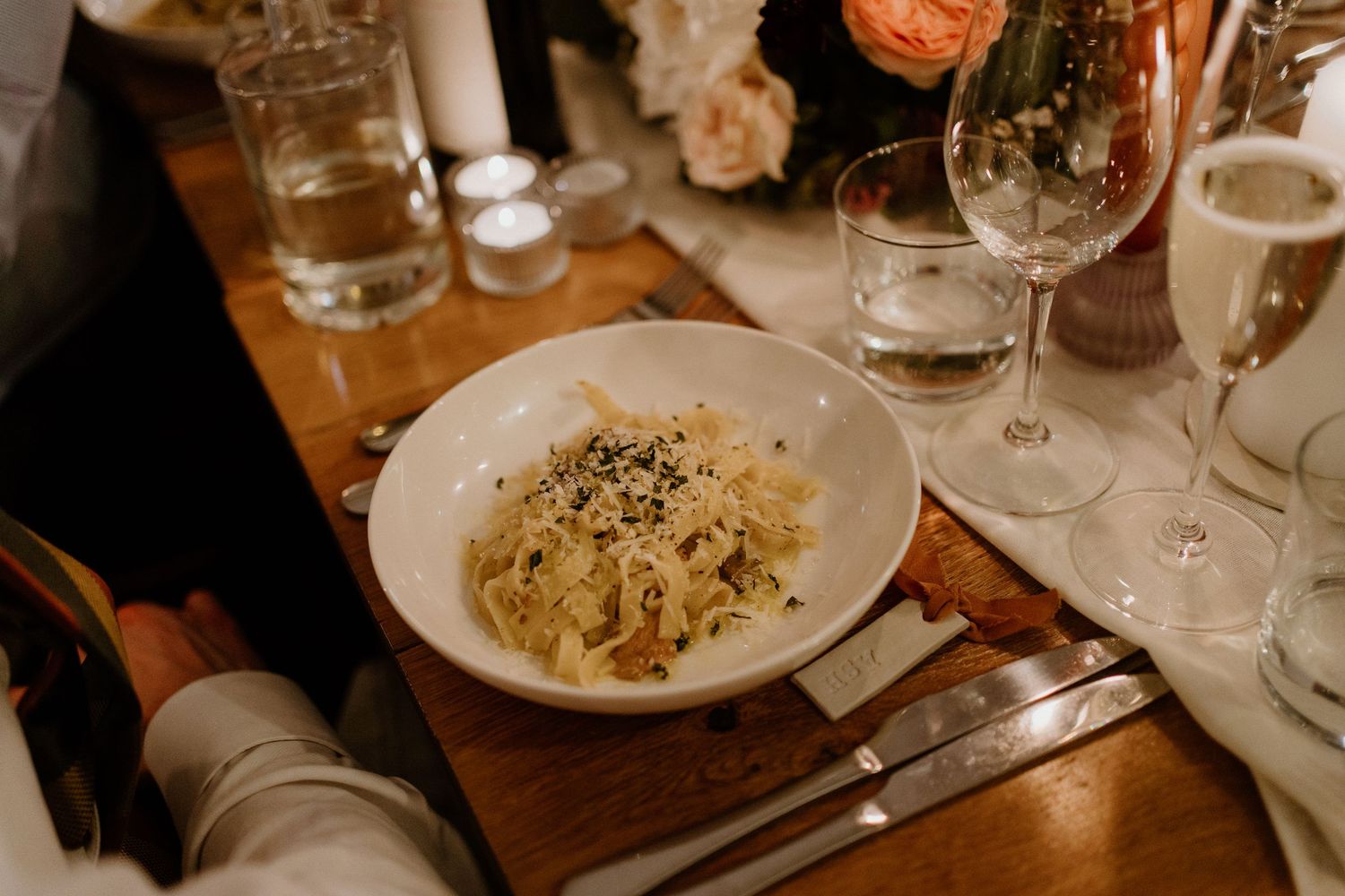Overhead view of a pasta dish served in a white bowl at an elegant wedding reception table.