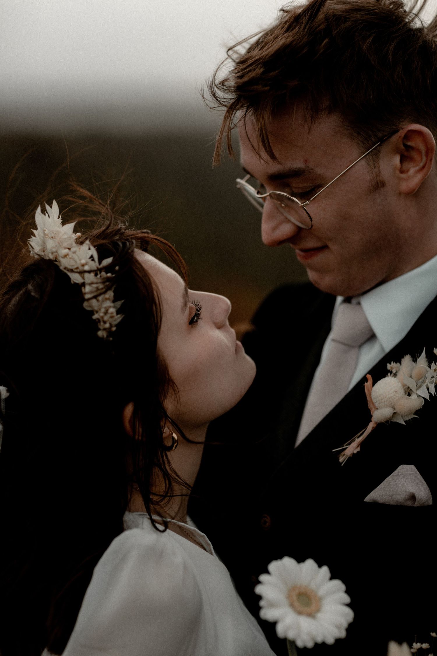 Intimate wedding portrait with soft lighting and delicate white floral details.