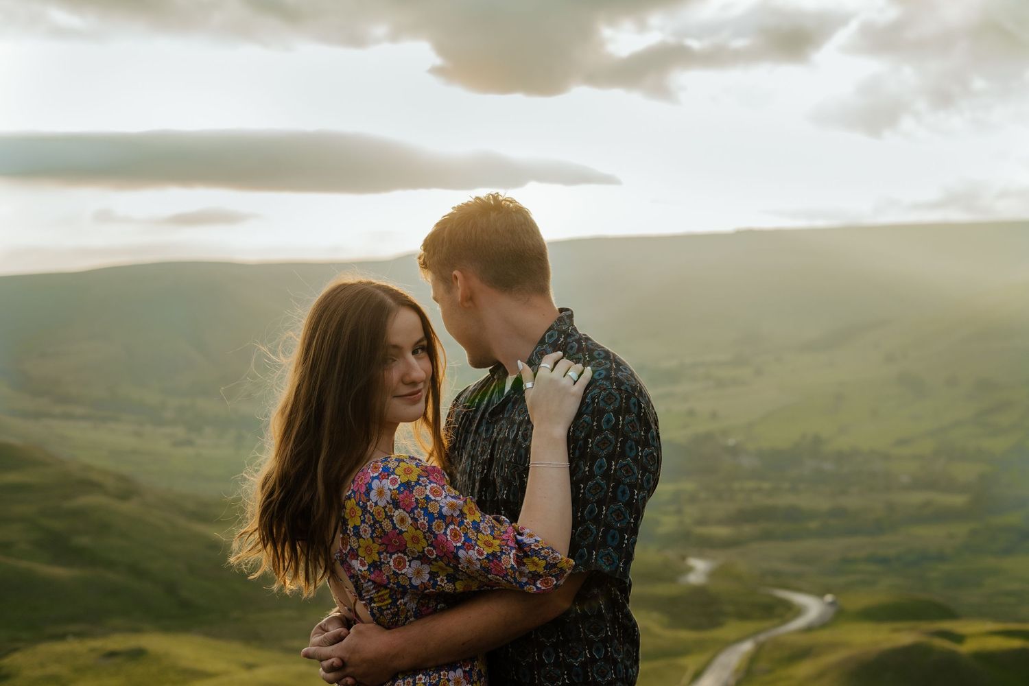 Romantic couple embracing and gazing at each other on a hilltop at golden hour.