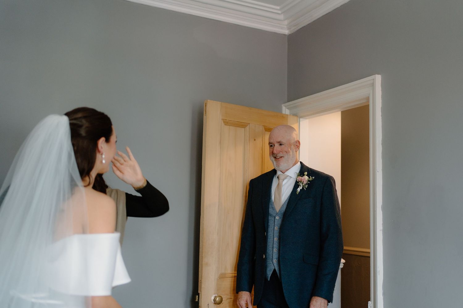 Emotional father of bride smiling as he sees daughter in wedding dress for first look reveal.