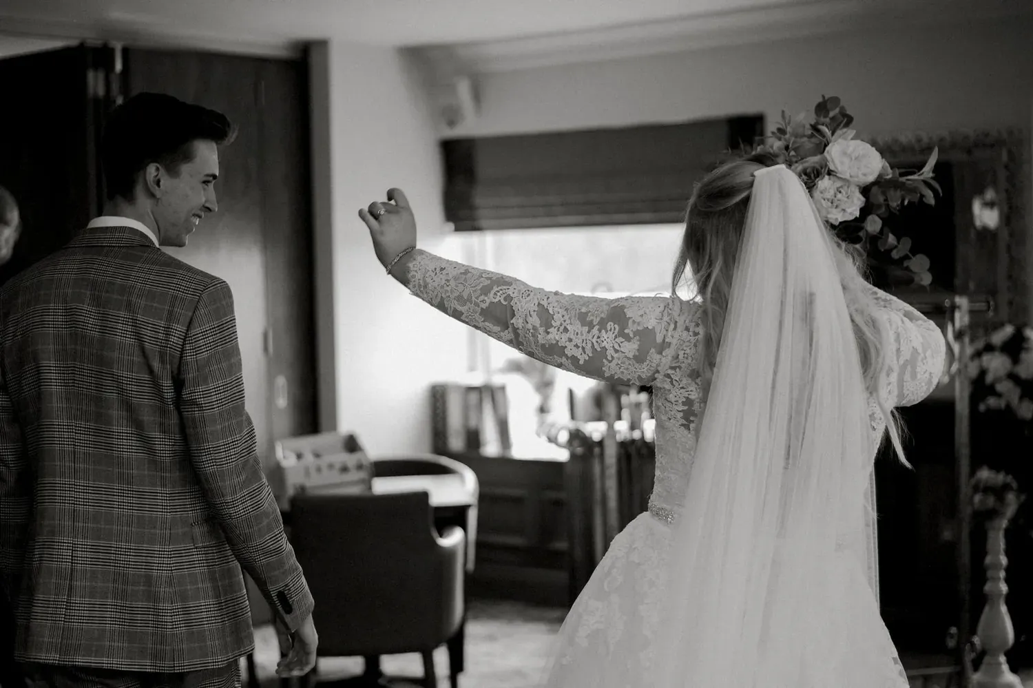 Black and white photo showing a playful moment between newlyweds indoors.