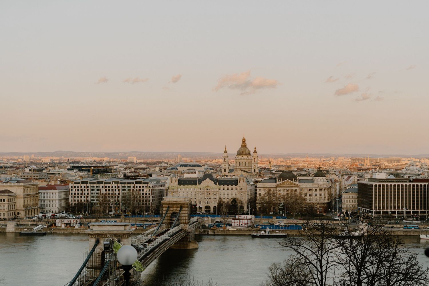 Aerial view of Budapest's cityscape at sunset with the iconic Parliament Building and Chain Bridge over the Danube River.
