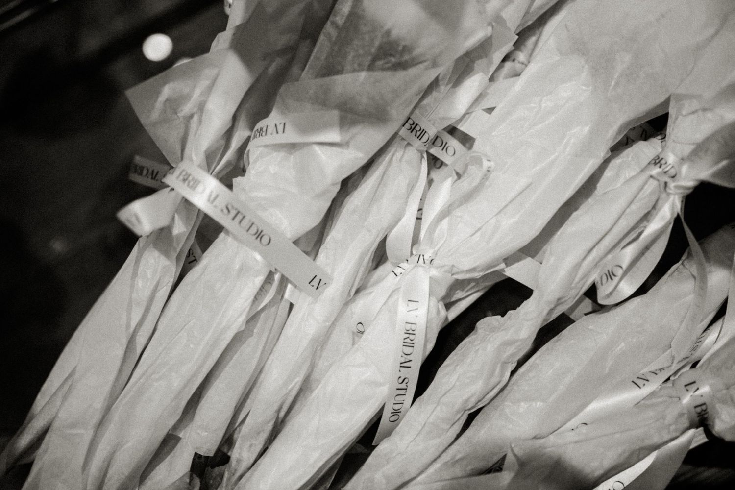 An artistic black and white photograph showing white dress shirts hanging on clothes hangers.
