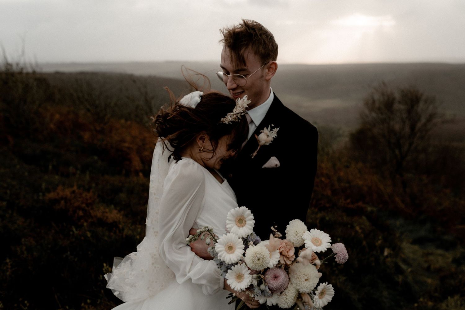 Moody wedding photograph with dramatic lighting and elegant floral bouquet.