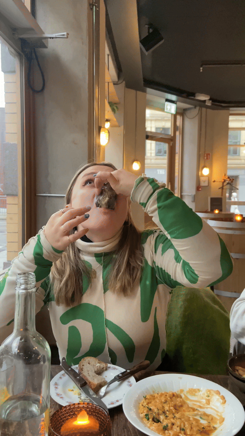 Woman eats oyster and pretends to enjoy it but the disgust shows on her face.
