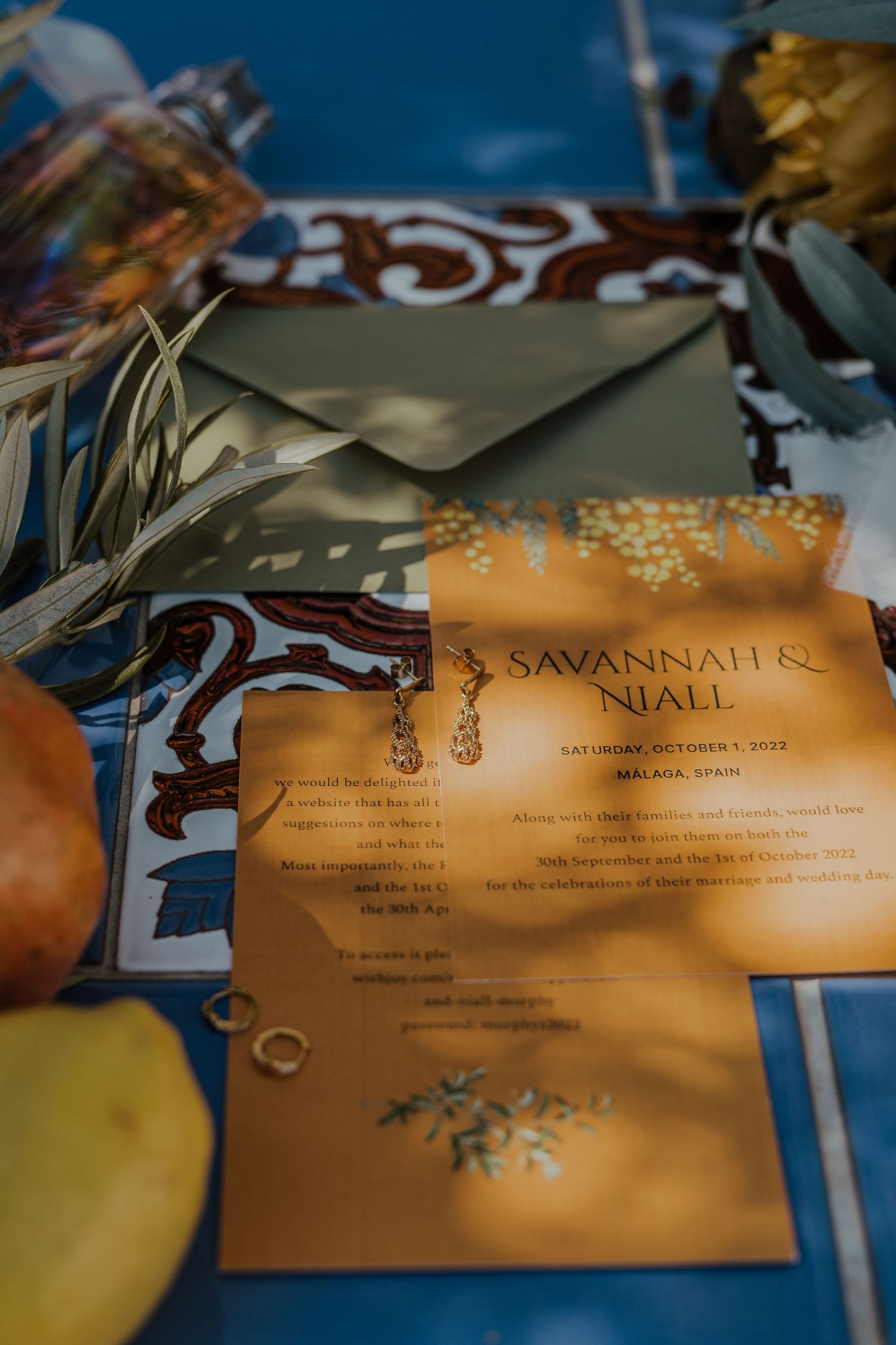 Elegant gold wedding invitation suite for Savannah and Niall in Malaga Spain on a blue tile surface.