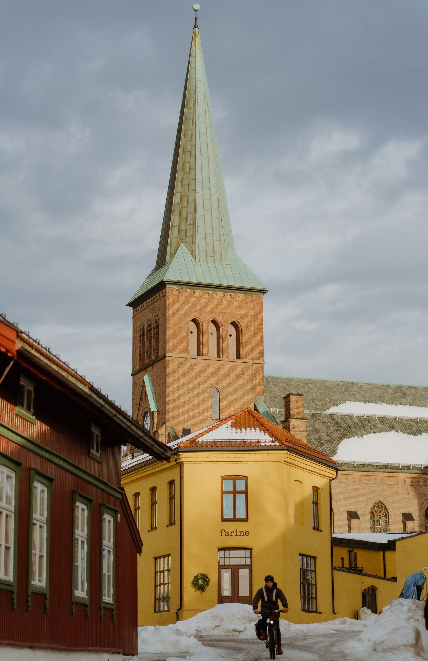Church spire rises above colorful buildings in a snowy Nordic town scene.