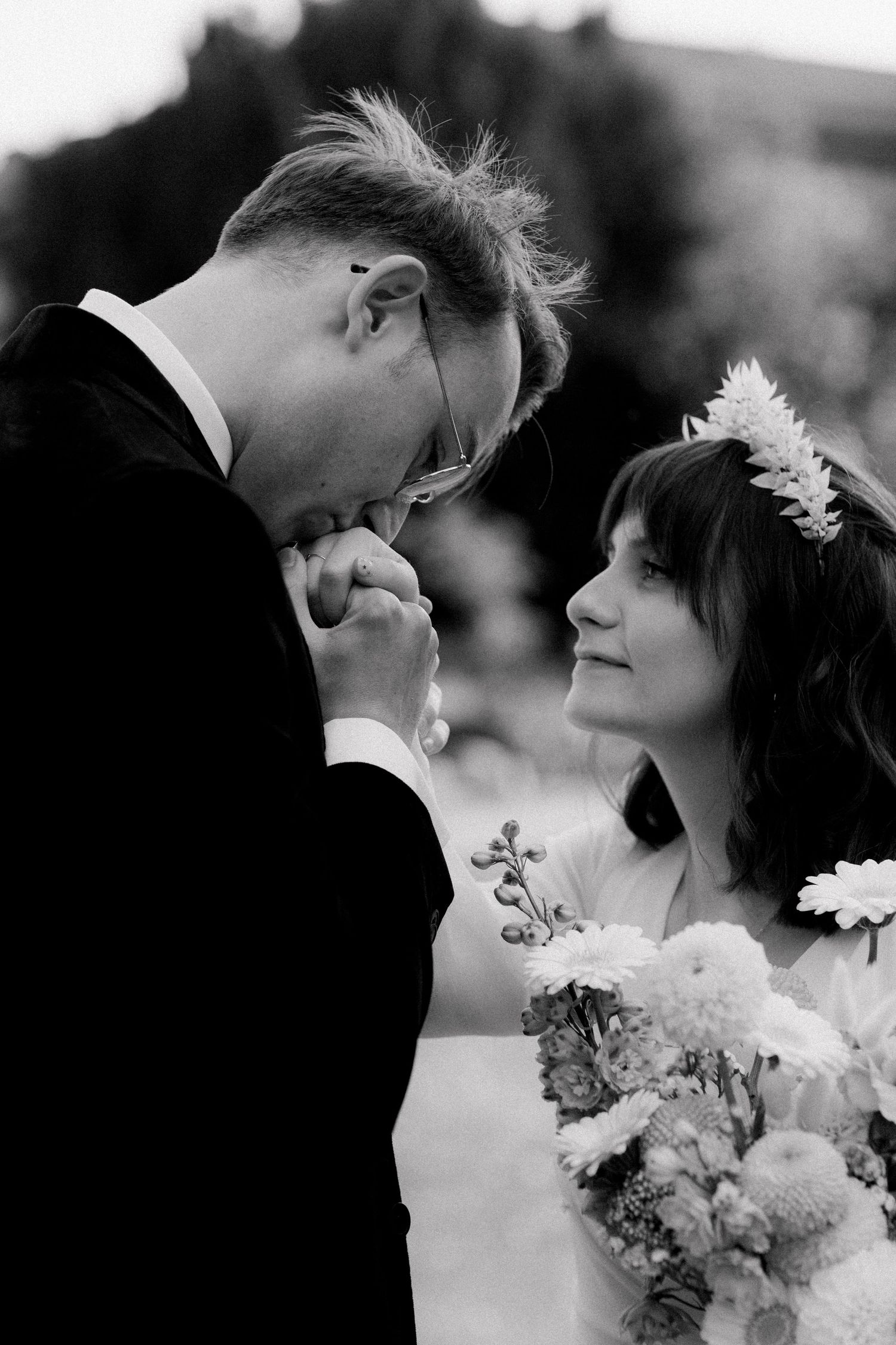 Black and white wedding portrait capturing an intimate moment between a couple with a delicate bridal bouquet.