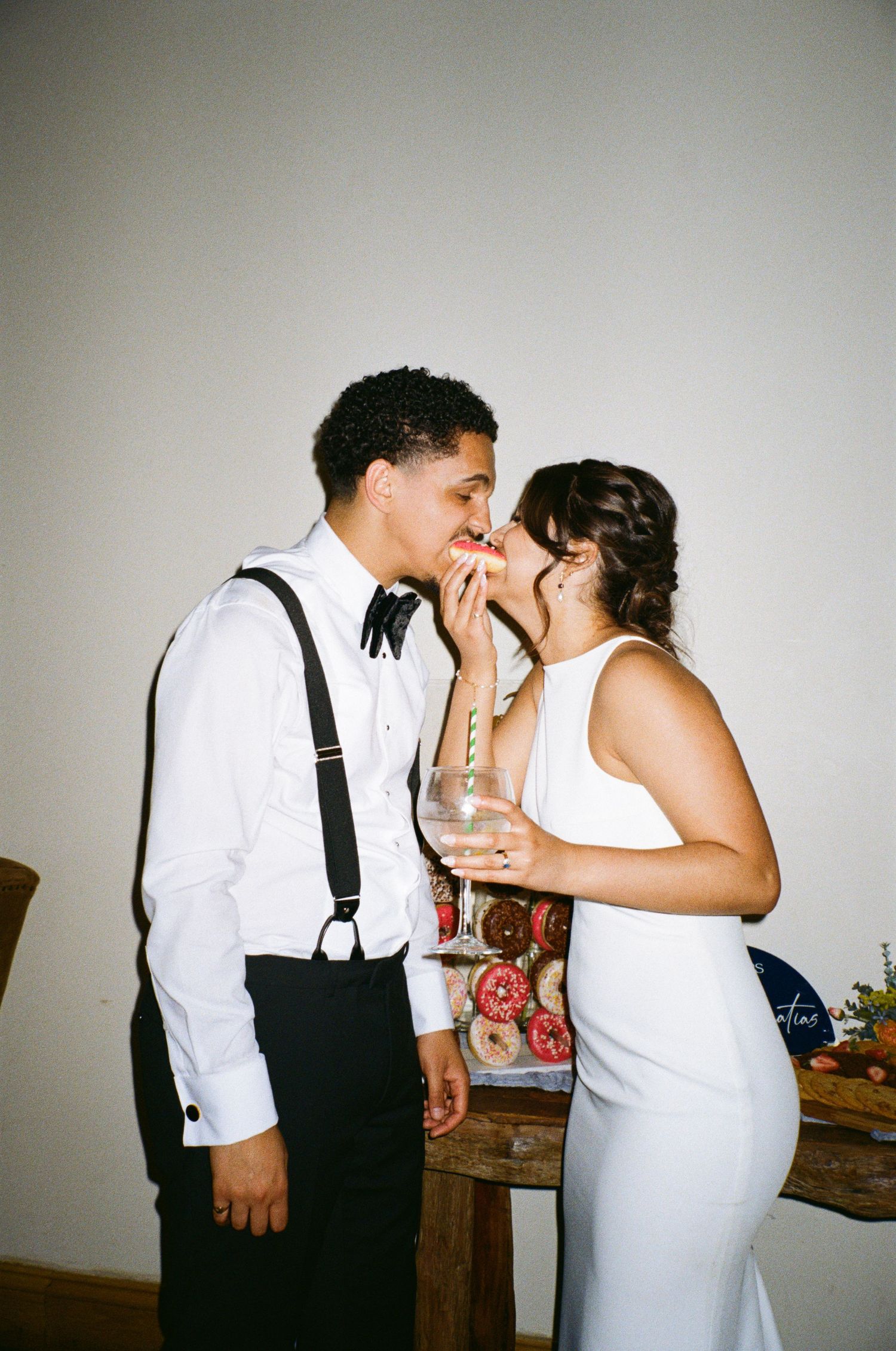 Bride and groom sharing a sweet moment eating together at wedding reception indoors.