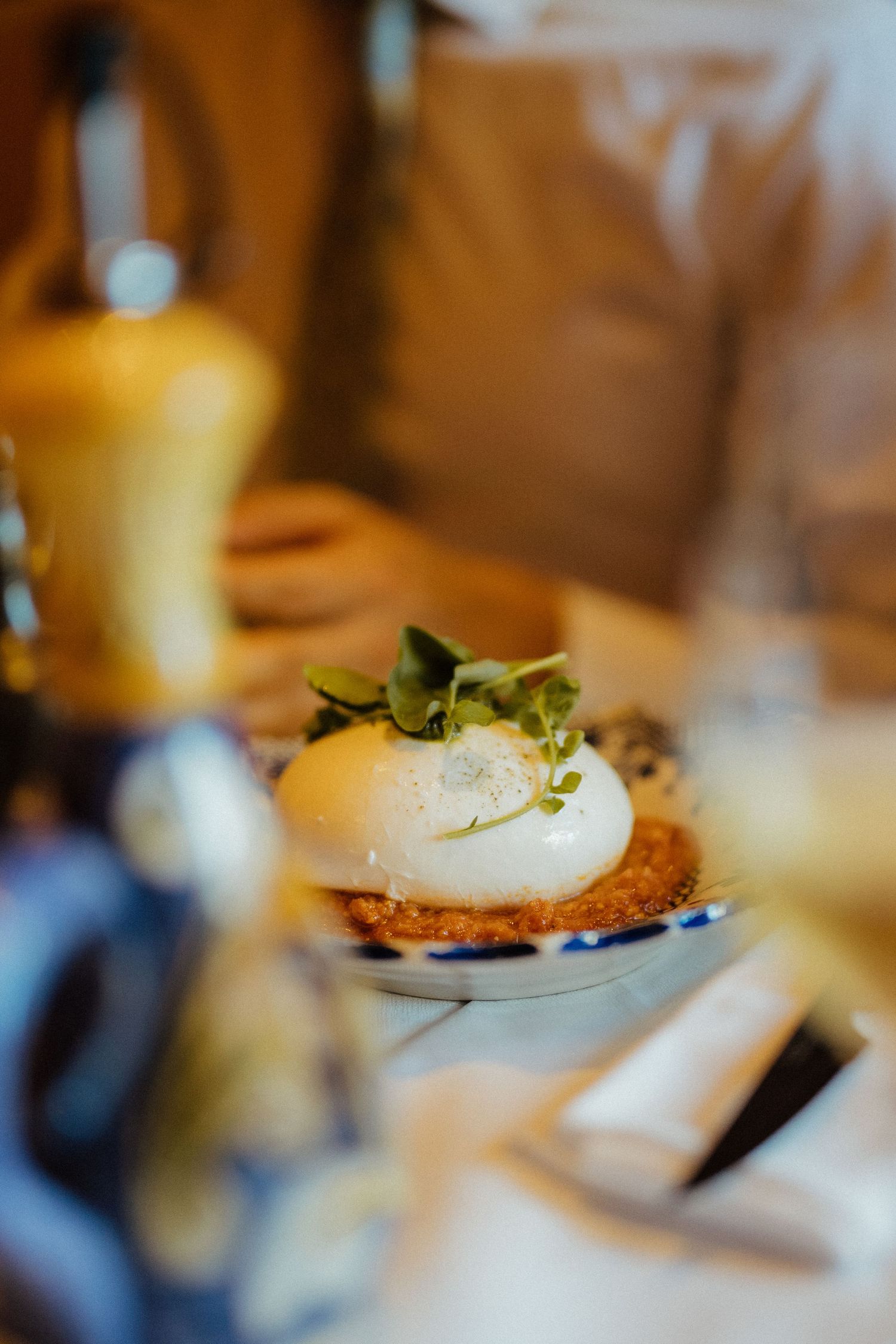 A gourmet poached egg sits atop a crispy base garnished with fresh microgreens in warm lighting.
