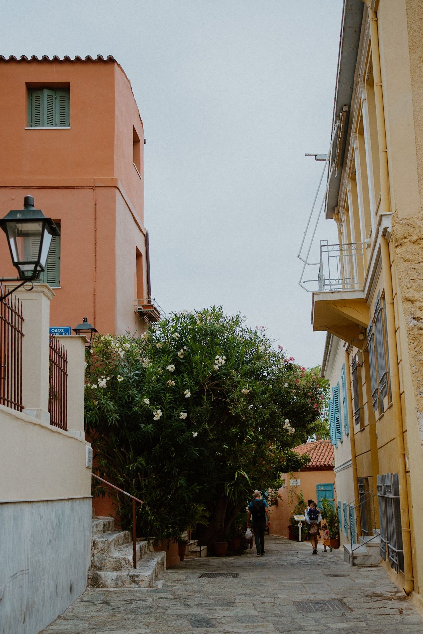 Colorful buildings line a narrow cobblestone street in a Mediterranean neighborhood with traditional architecture.