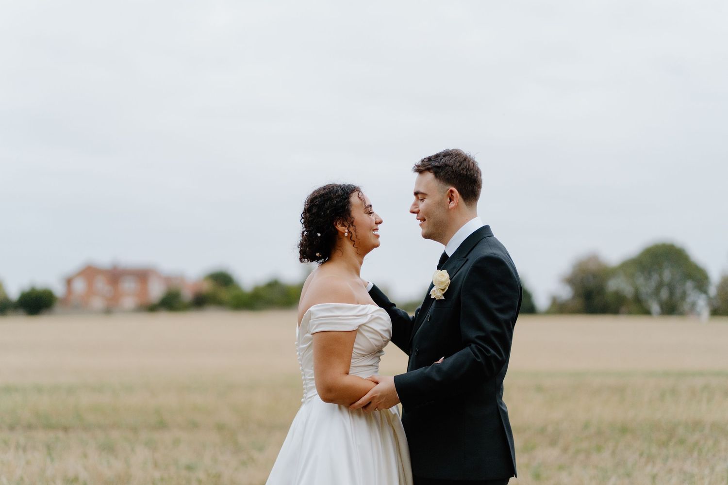 Bride and groom share a tender moment in a golden field on their wedding day.