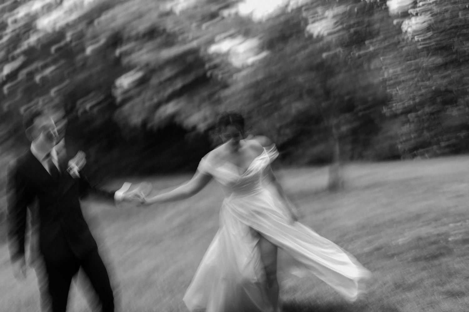 Blurred artistic black and white photo of bride and groom dancing outdoors on wedding day.