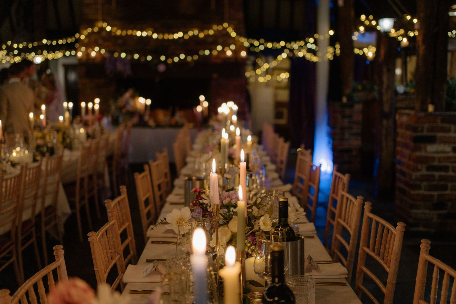 A romantic candlelit wedding reception with long tables, fairy lights, and warm glowing ambiance.