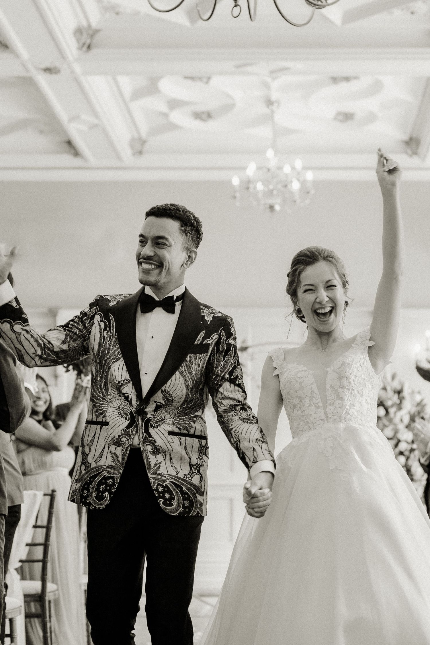 Black and white photo of joyful bride and groom celebrating at their wedding reception.
