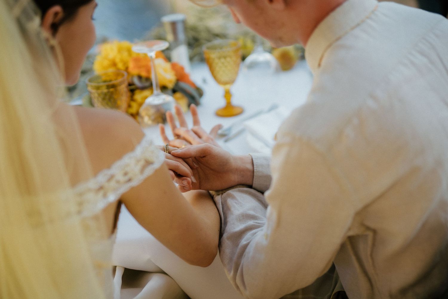 Groom placing a wedding ring on bride's finger at elegant reception table with golden goblets.