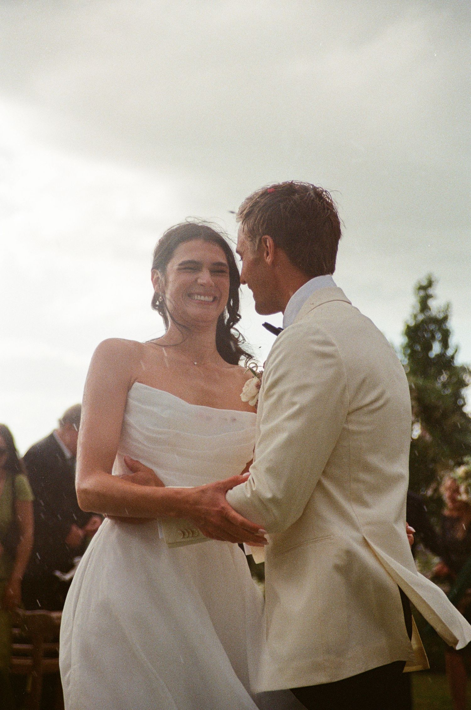 Joyful bride and groom sharing first dance at outdoor wedding ceremony.