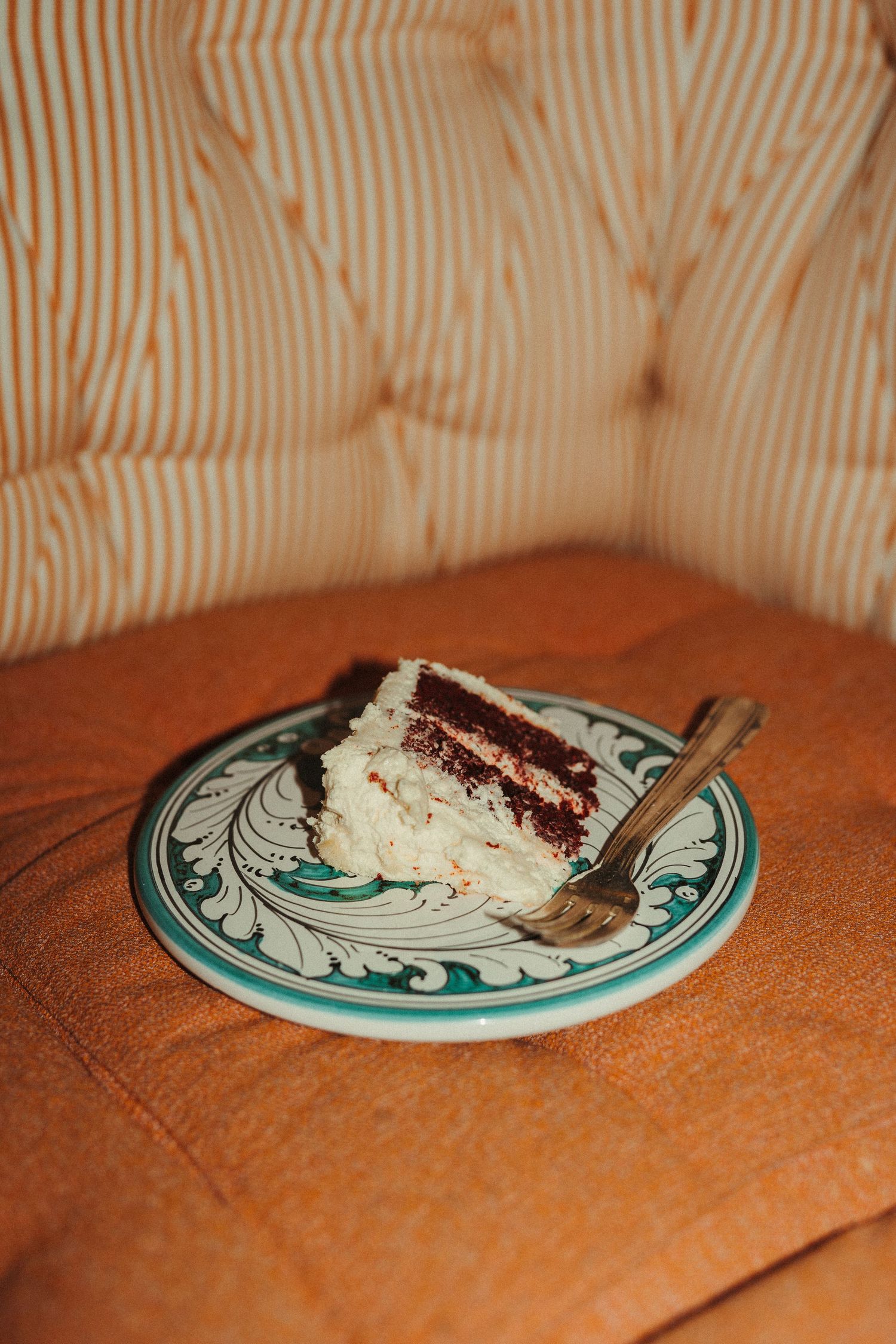 Slice of layered chocolate cake with white frosting on a decorative ceramic plate at a wedding.