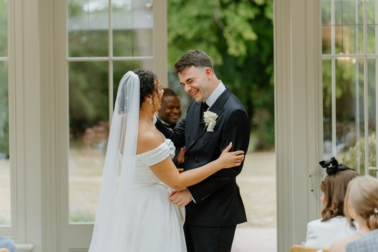 Bride and groom laughing together during outdoor wedding ceremony.