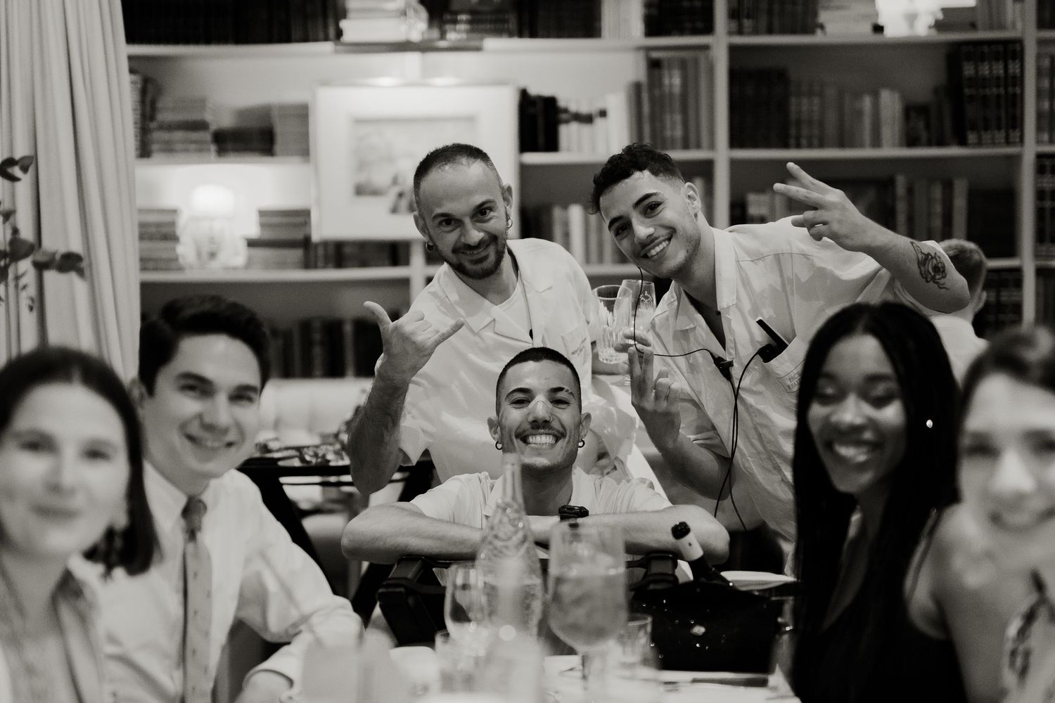 Group of smiling friends posing together at a dinner party in black and white.