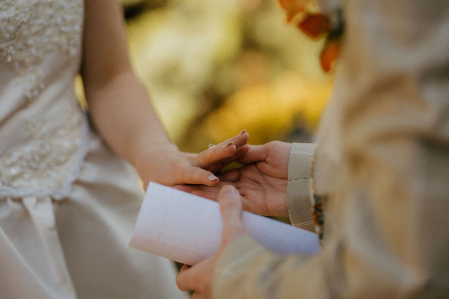 Close-up of groom placing wedding ring on bride's finger during emotional outdoor ceremony.