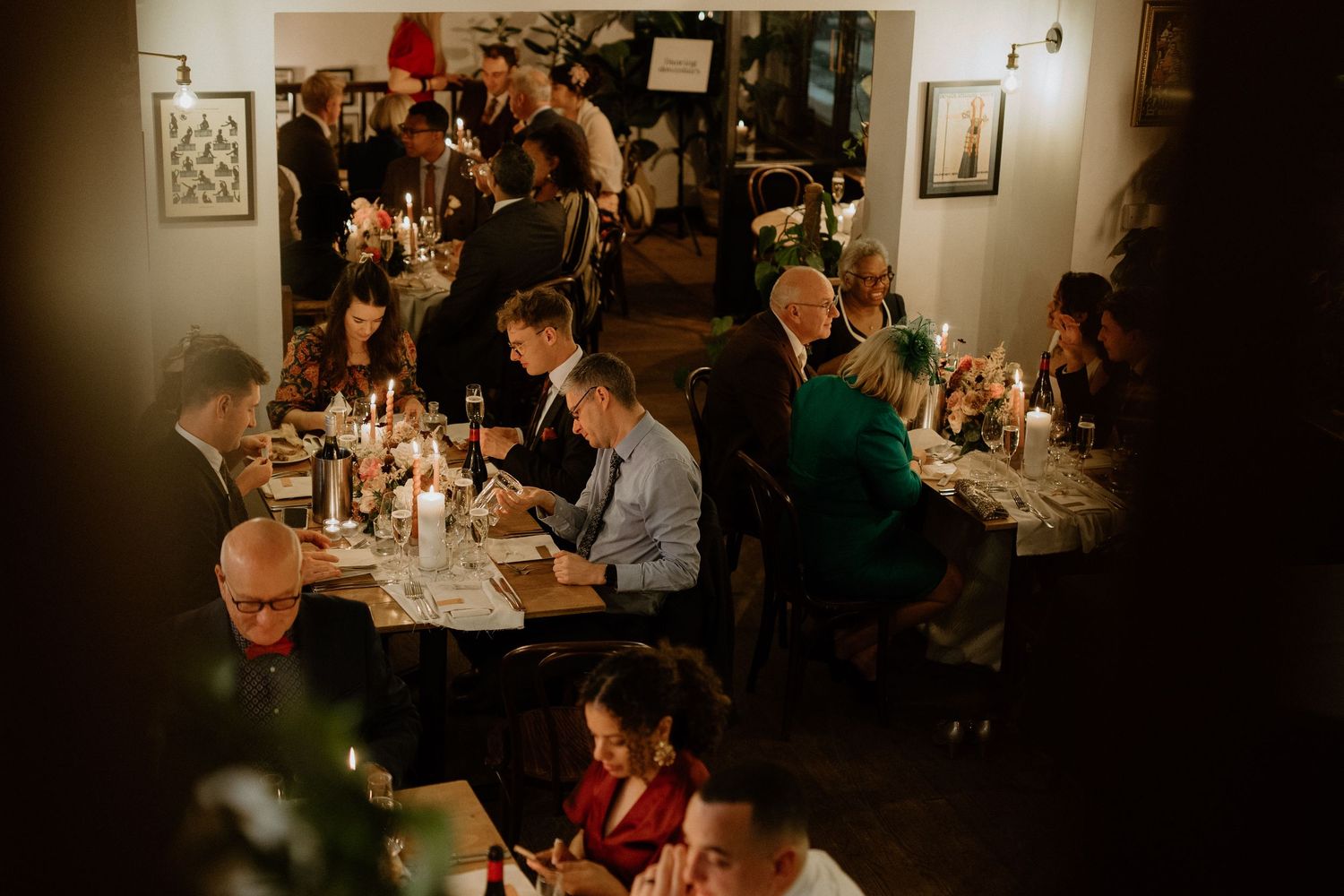 Overhead view of wedding guests dining at candlelit tables in an intimate restaurant reception venue.