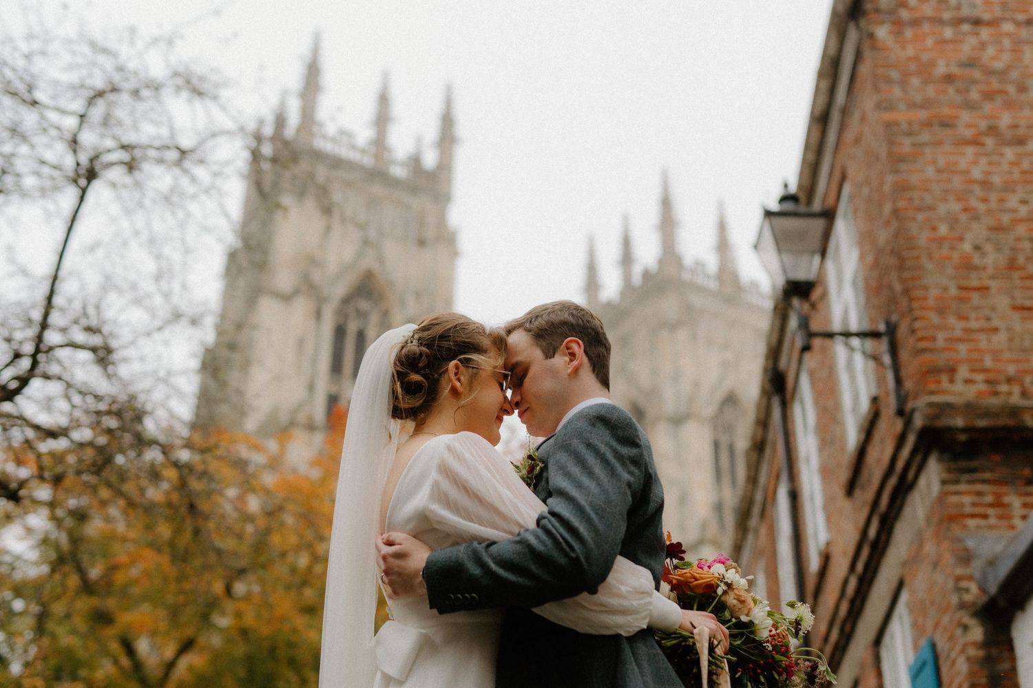 Romantic bride and groom touching foreheads outside York Minster on their wedding day.