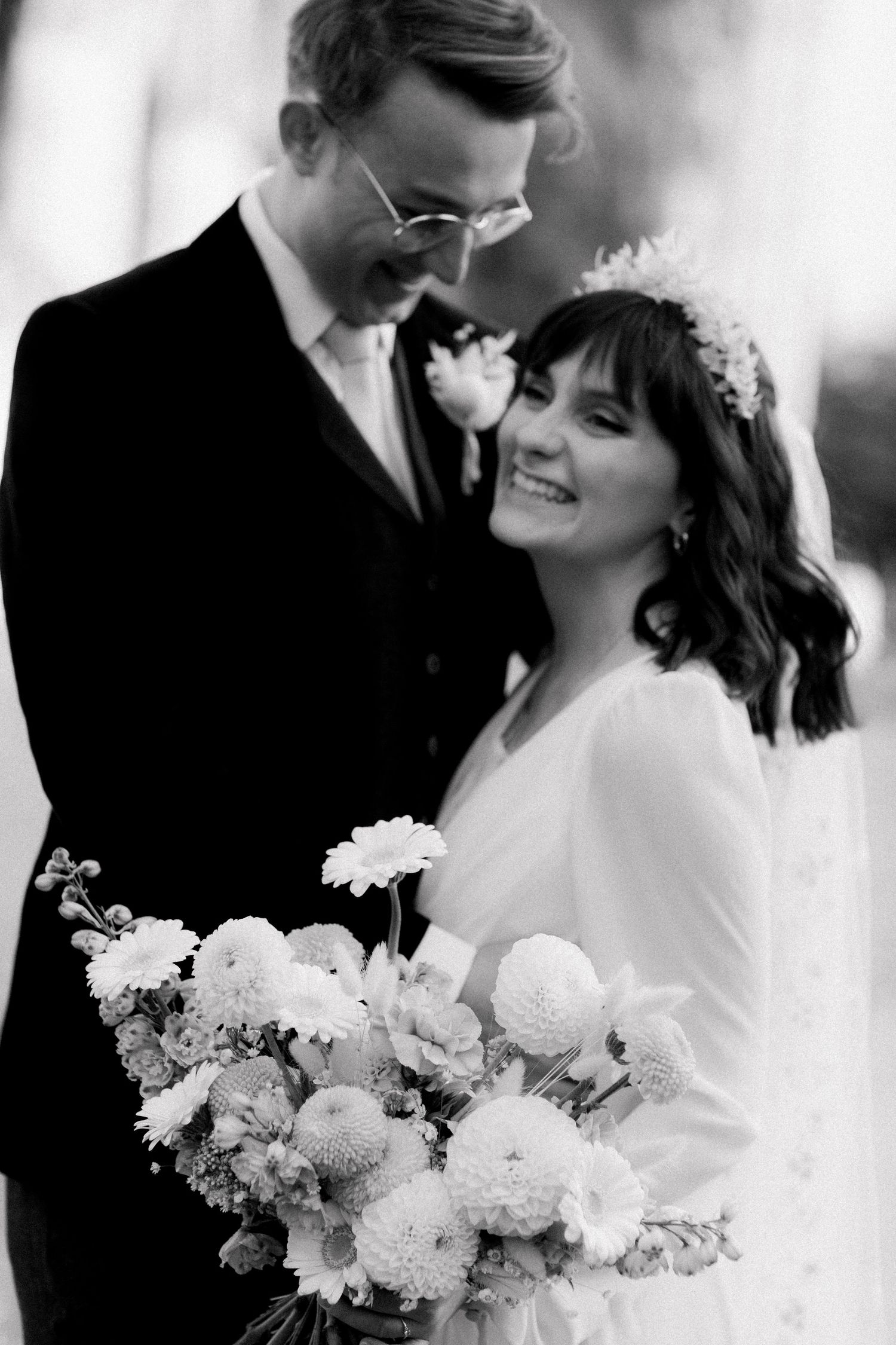 Romantic black and white wedding portrait with the couple sharing a loving glance and elegant white bouquet.