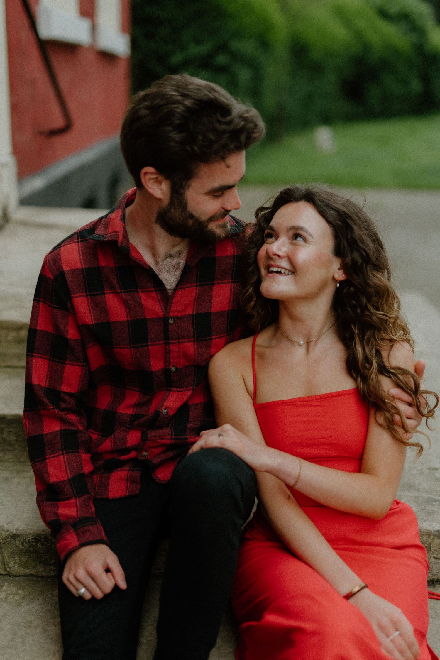 Couple sharing a tender moment sitting on stone steps, smiling at each other affectionately.