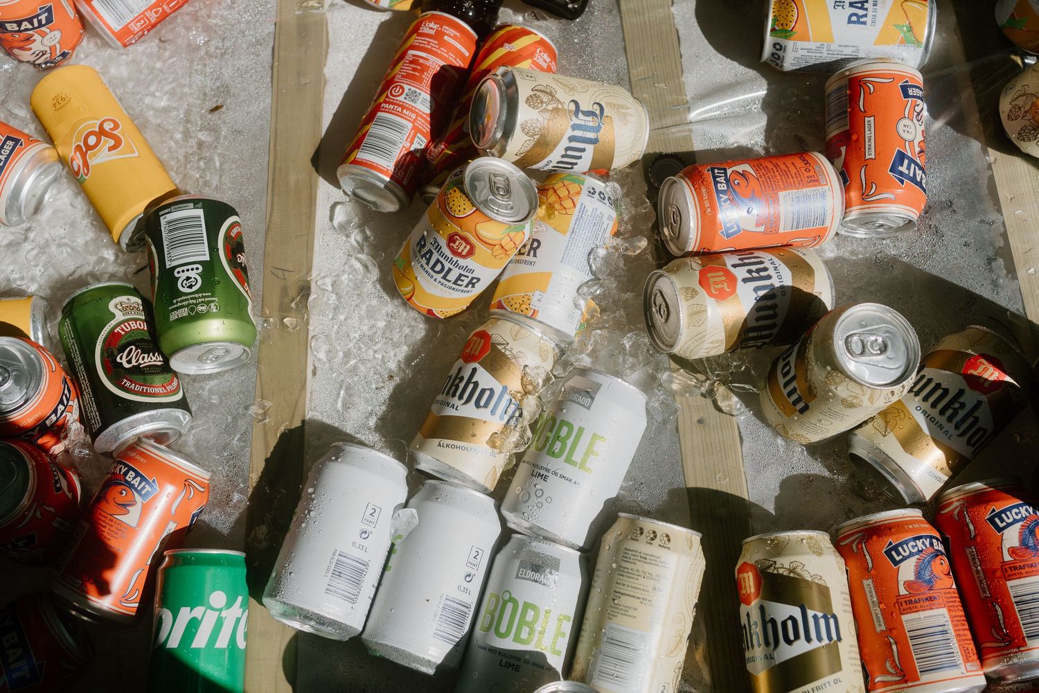 Overhead view of assorted empty beer and soda cans scattered on ground after party.