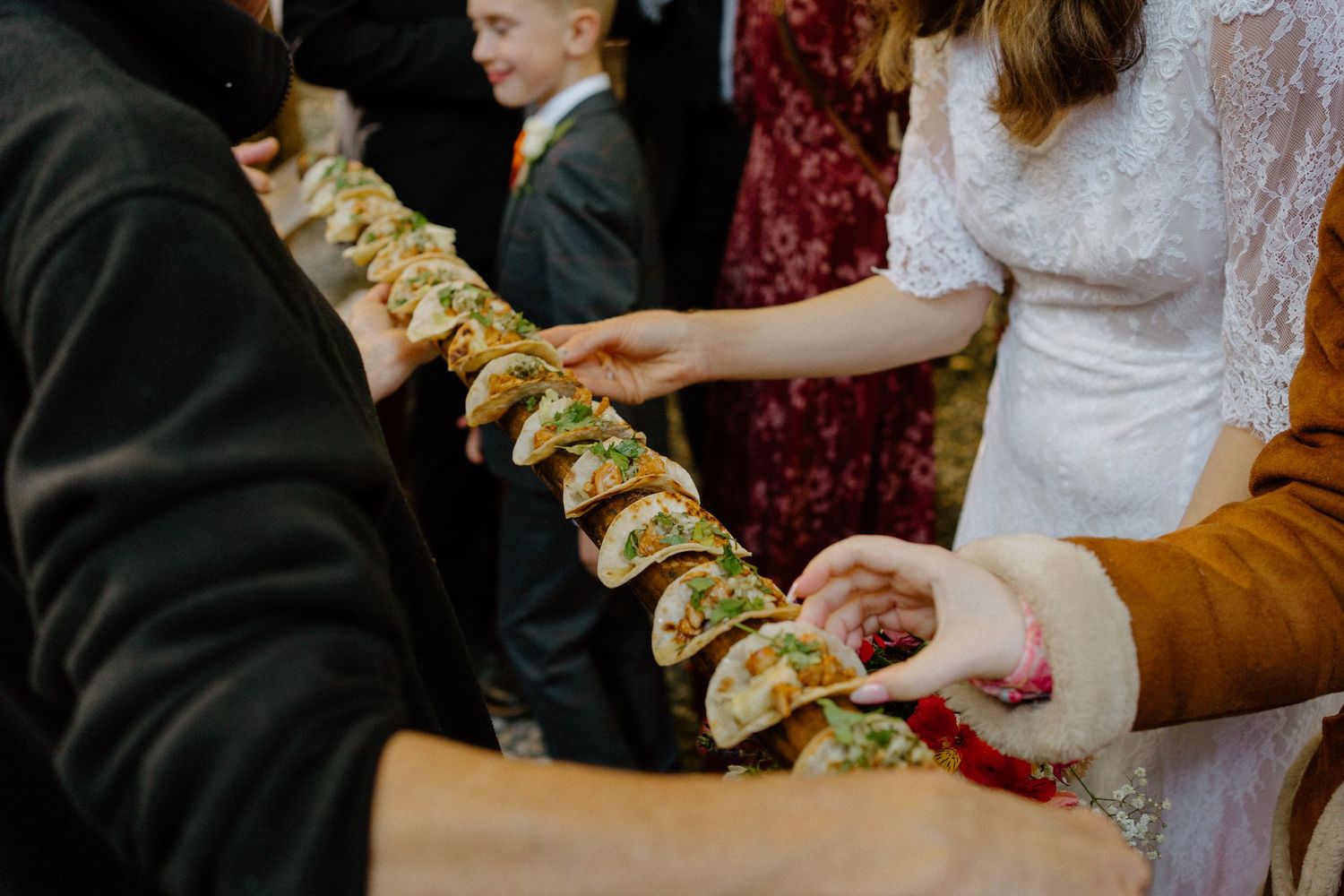 Long row of tacos being shared at a party or celebration gathering.