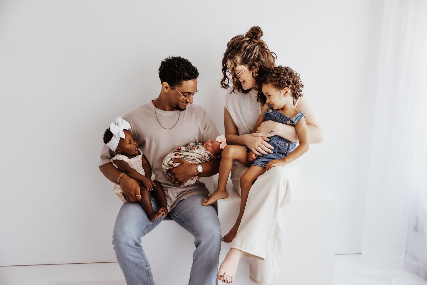Young family cuddling together during a relaxed lifestyle newborn photography session in Topeka, Kansas.