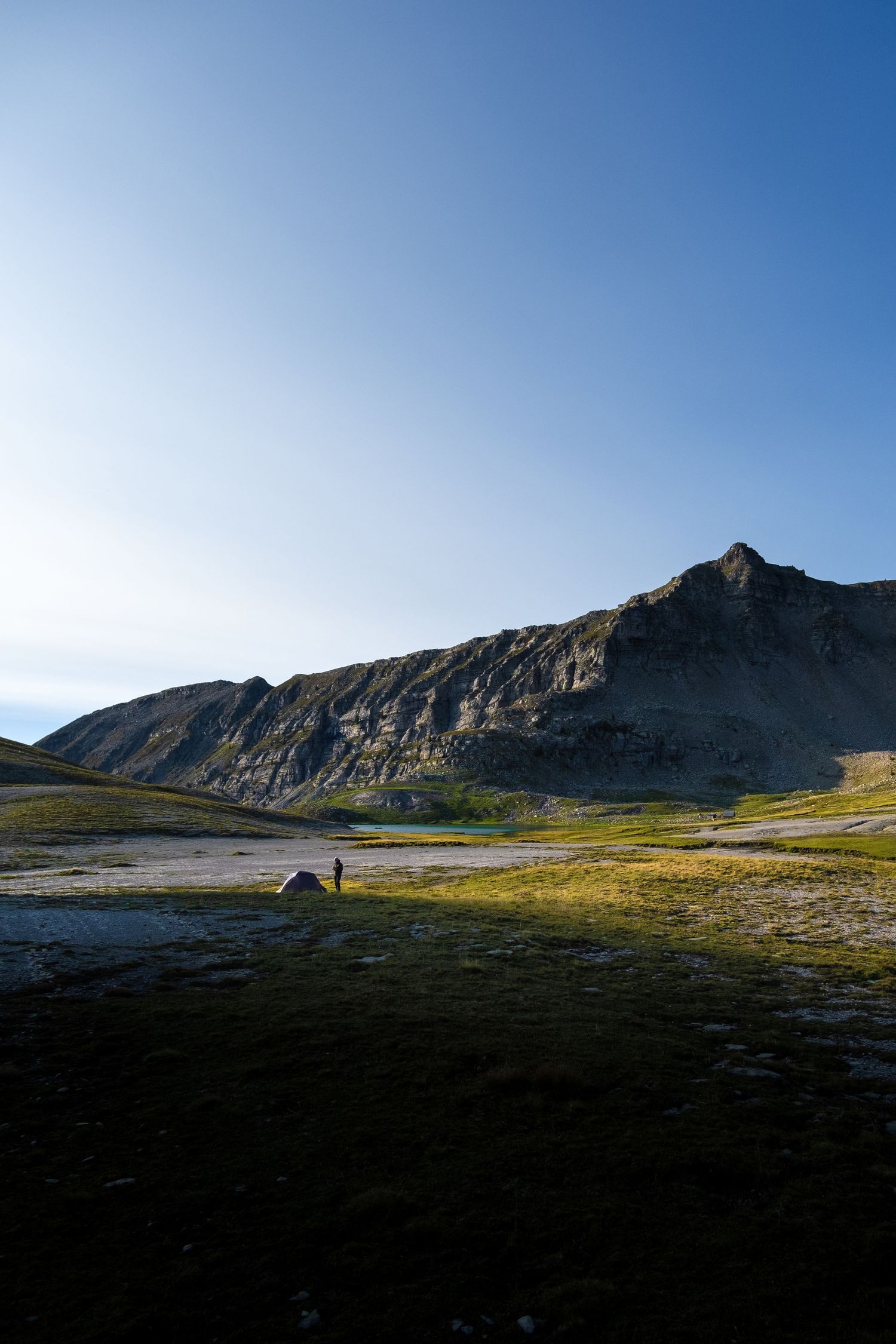 Photo de paysage en montagne, dans les Alpes. Un randonneur y a planté sa tente.
