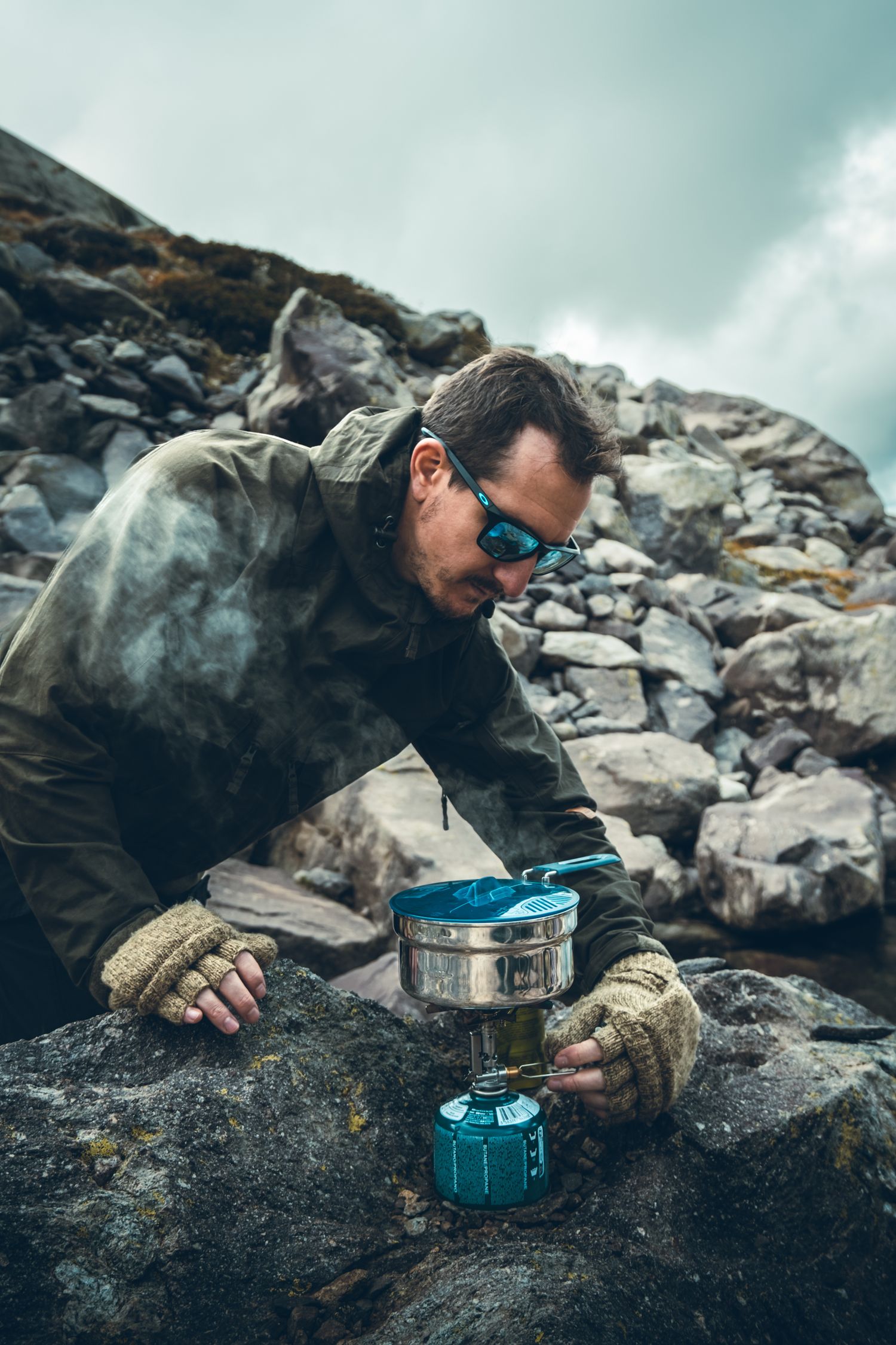 Photo d'un homme randonneur qui se fait à manger en montagne grâce à une popote et un réchaud
