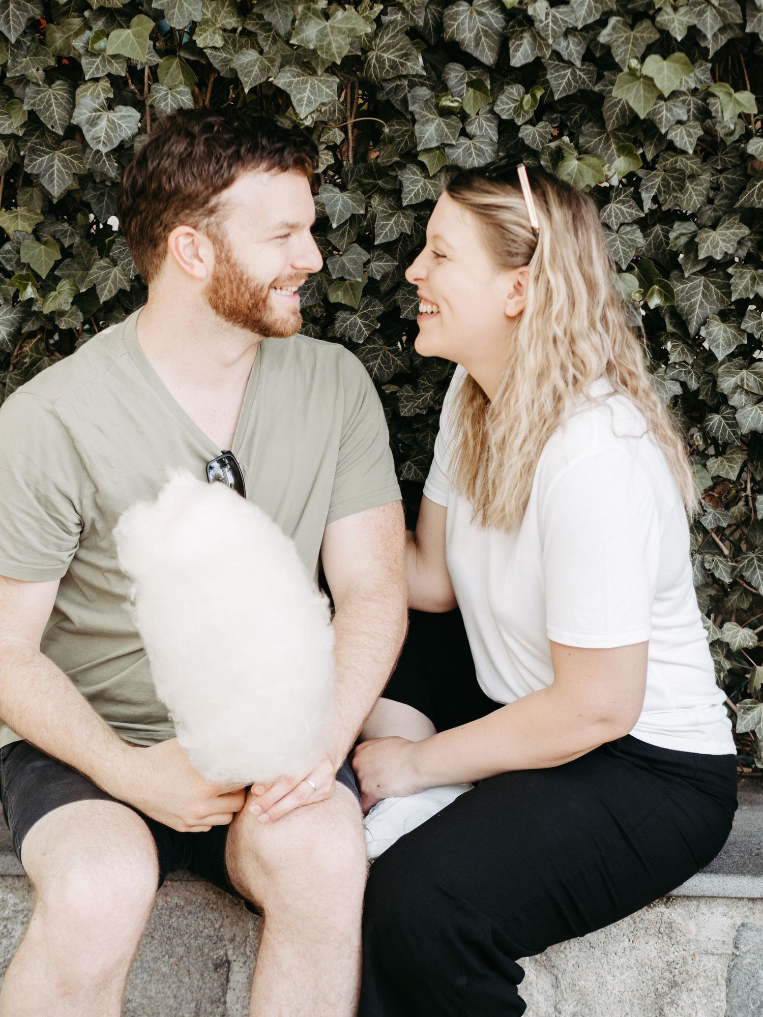 Casual outdoor couples photography session against an ivy-covered wall backdrop.