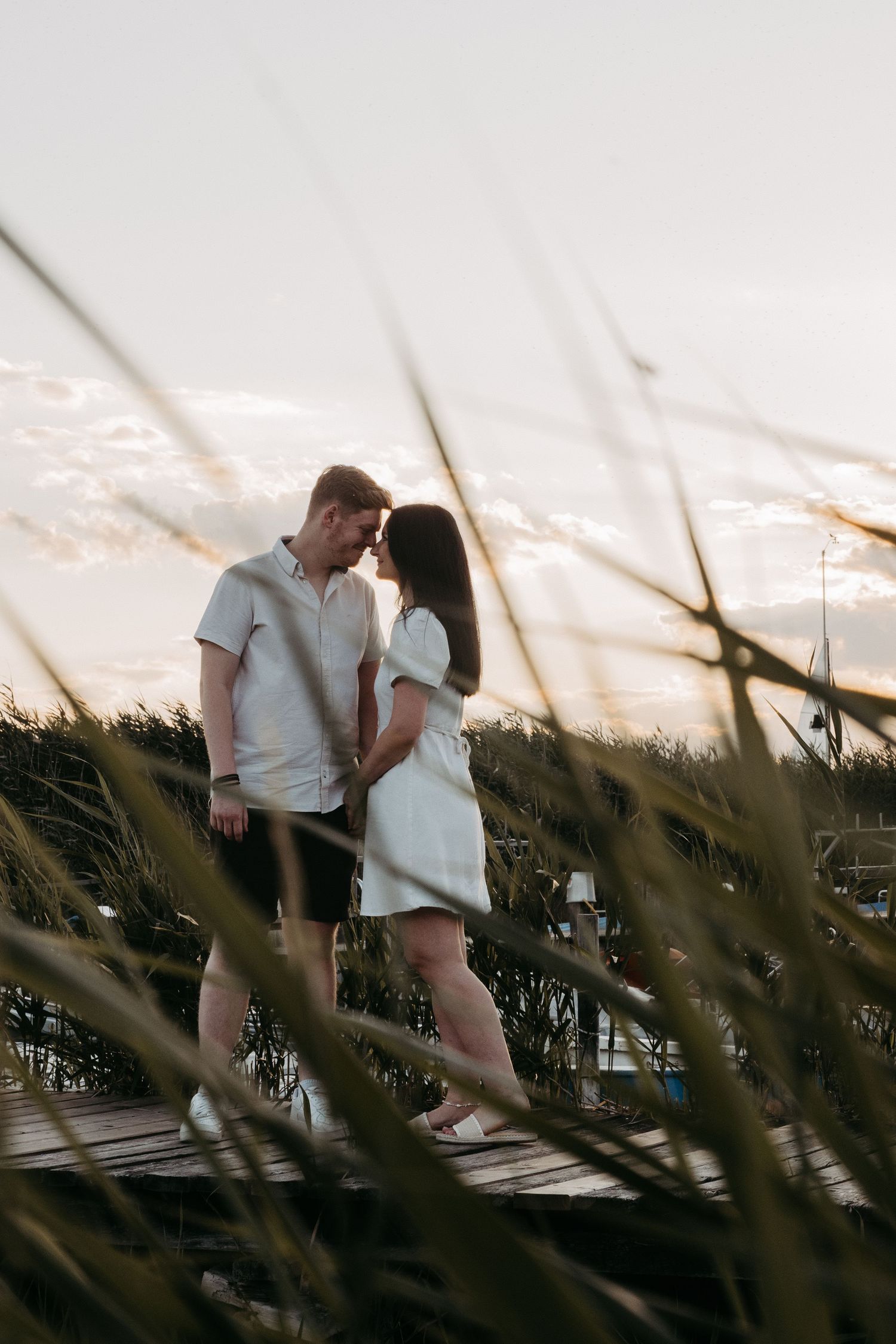 Silhouetted couple sharing intimate moments on boardwalk at dusk.